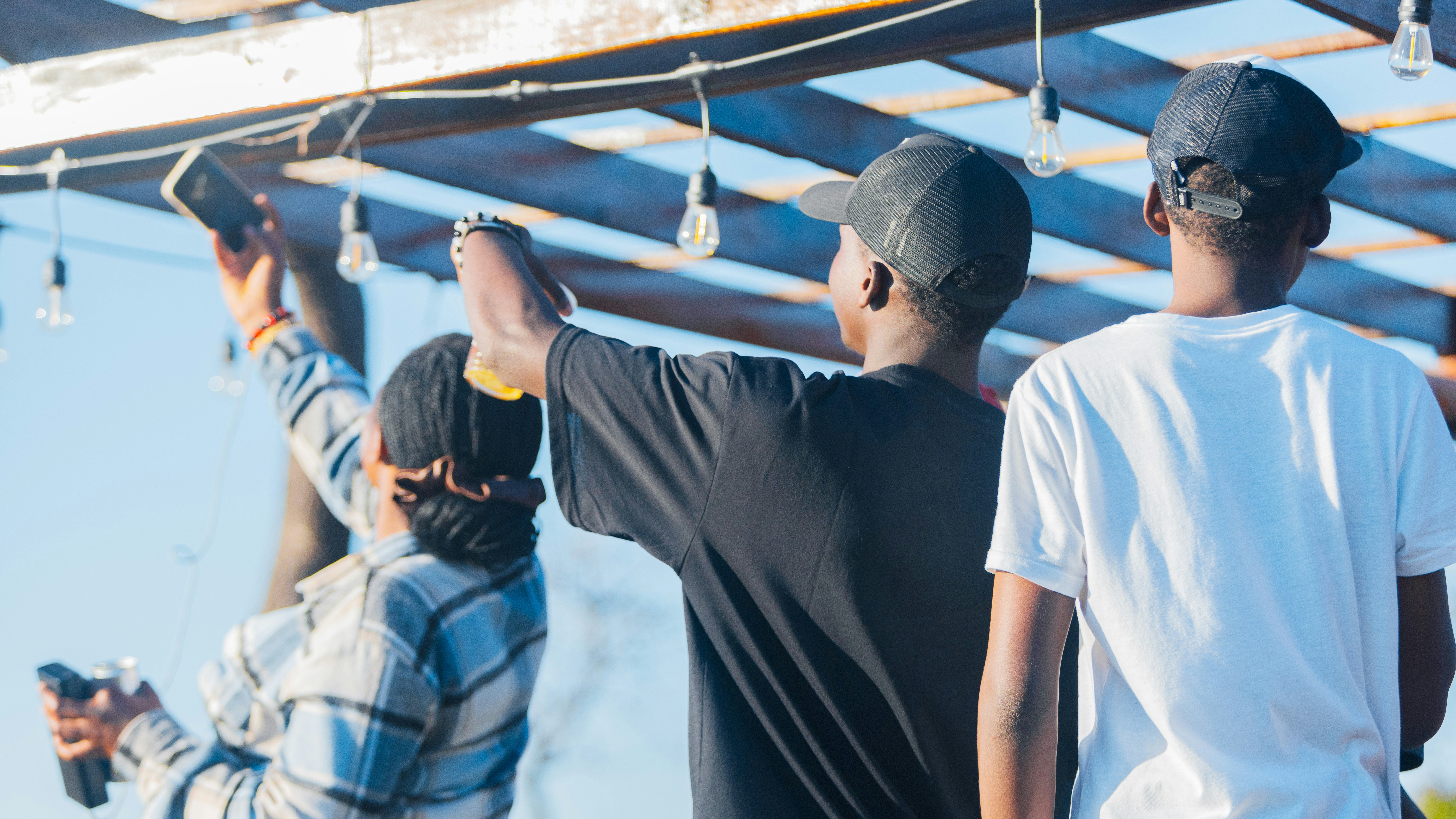 A group of workers standing under string lights and looking ahead together