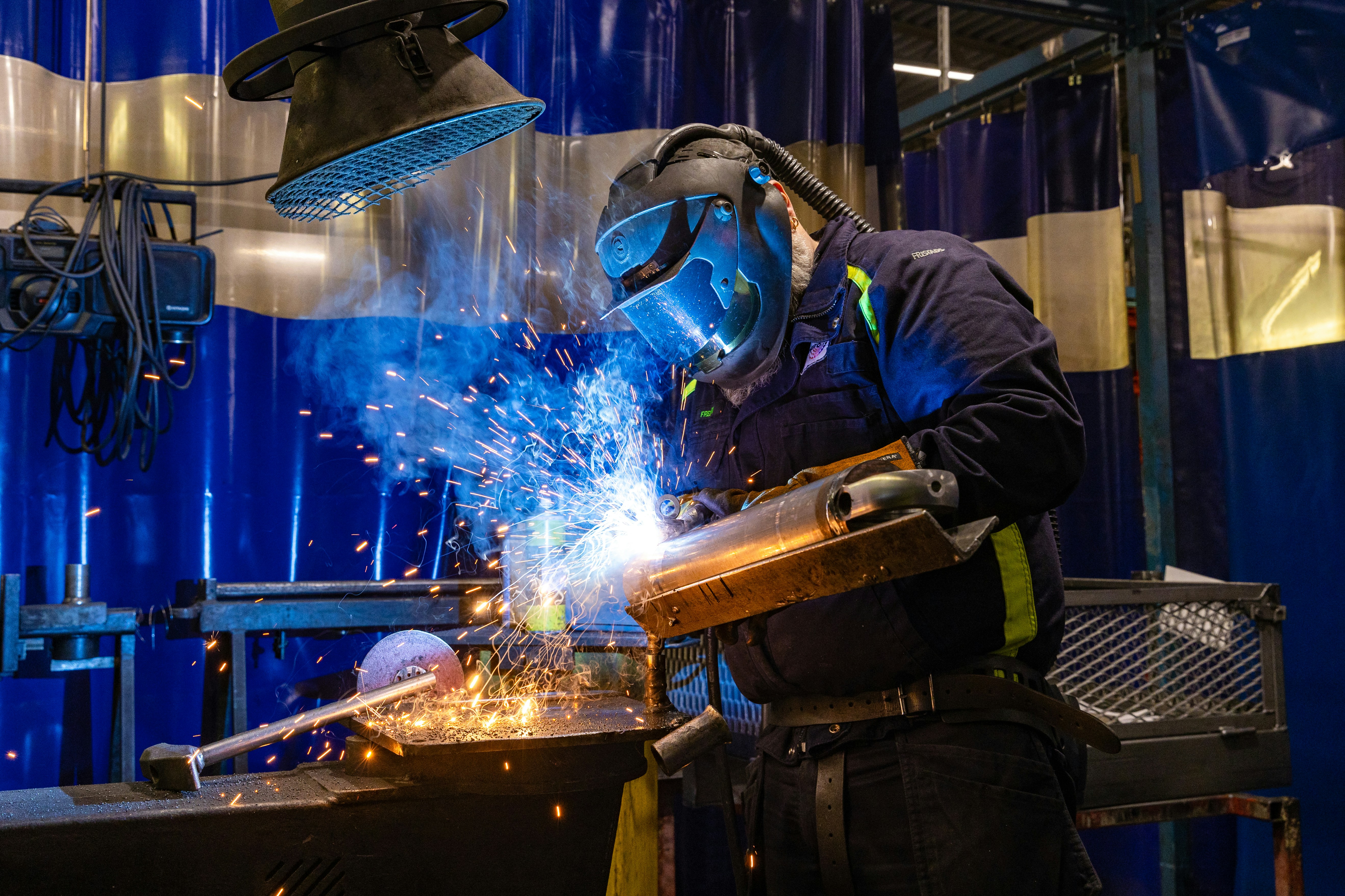Welder working with bright sparks inside an industrial workshop