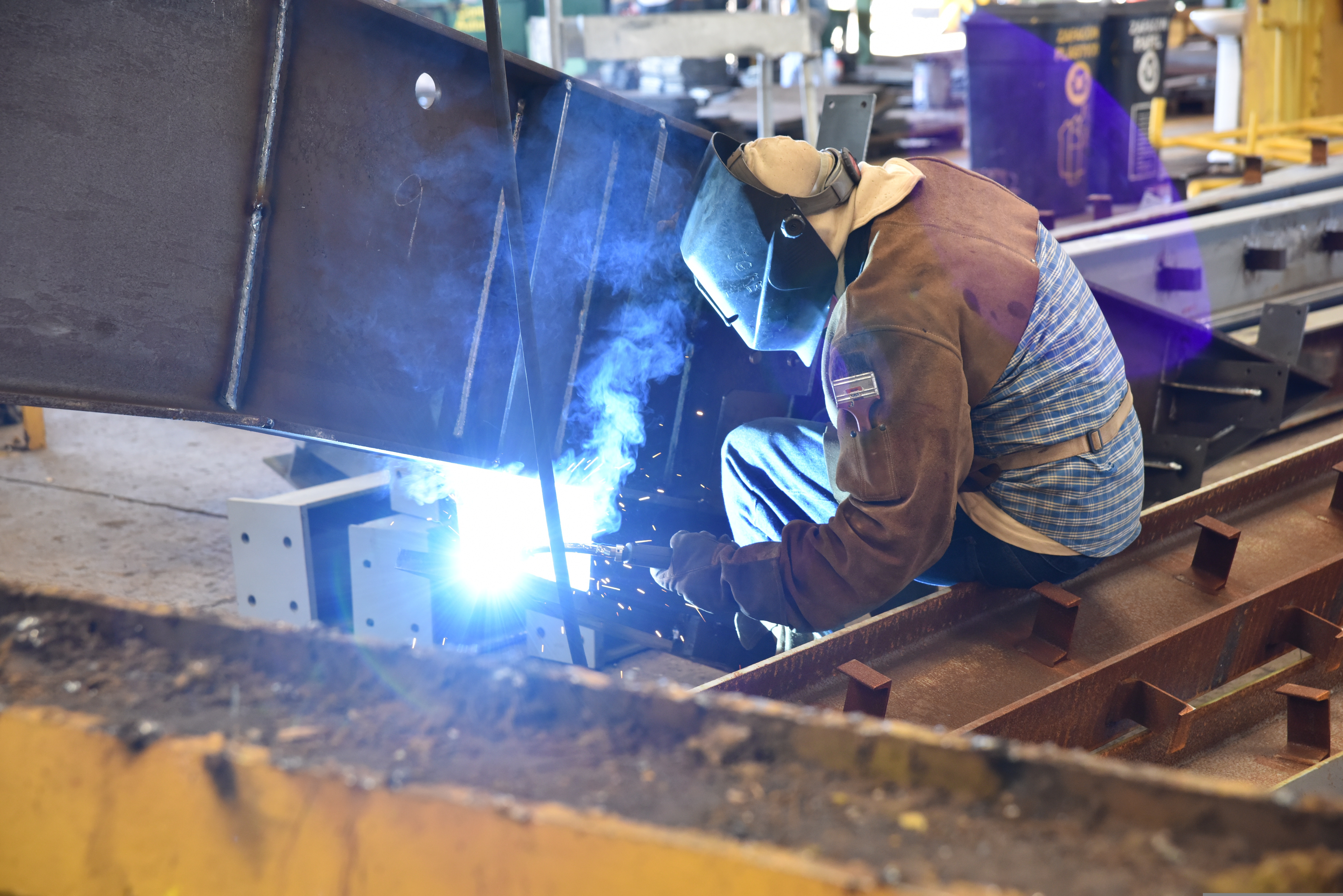 Worker welding a steel structure inside a fabrication facility
